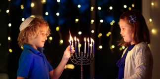 boy and a girl celebrate Hanukkah by lighting a menorah