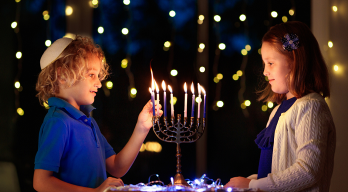 boy and a girl celebrate Hanukkah by lighting a menorah
