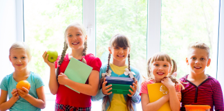 5 students stand in a row with back to school supplies