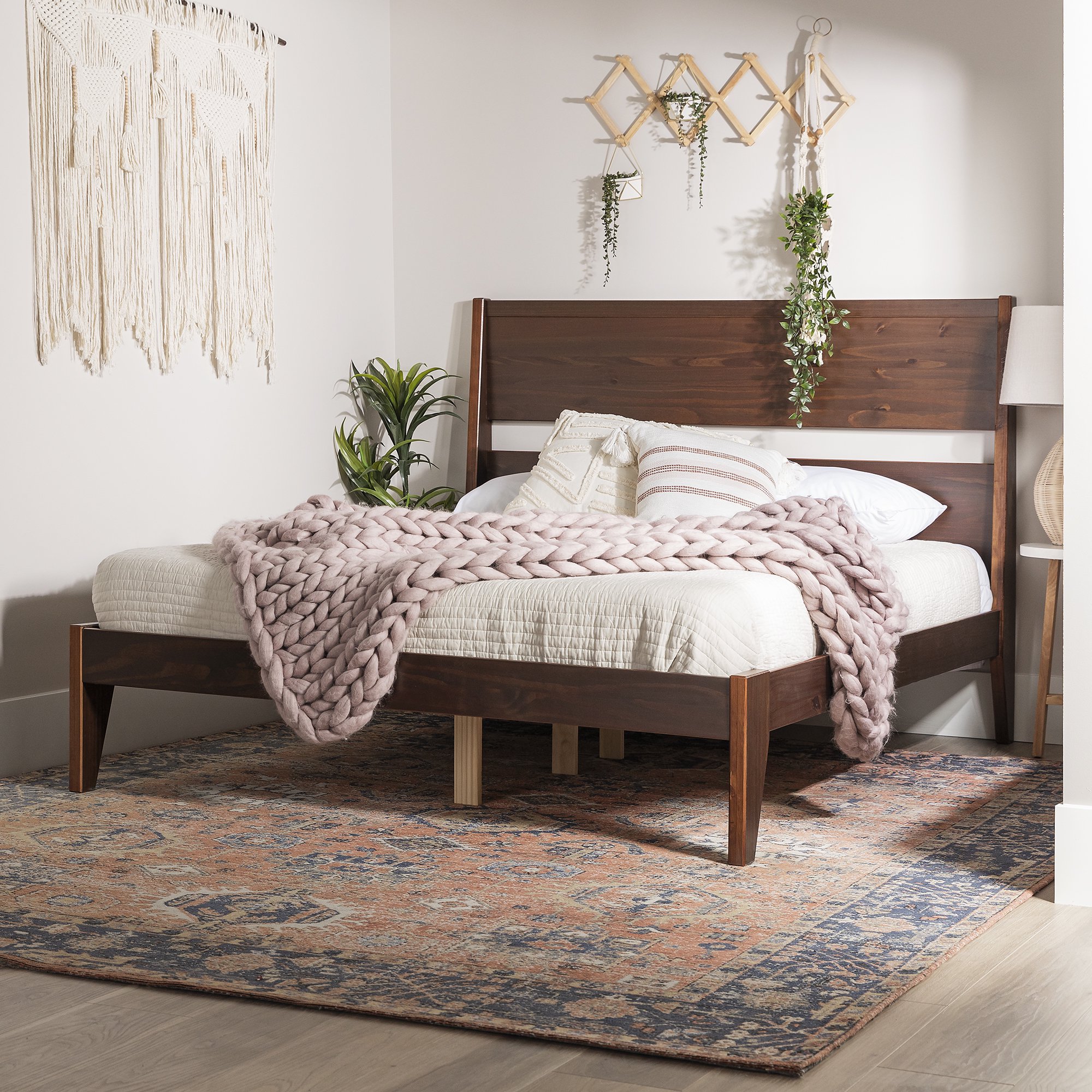 platform bed in walnut with cream bedding and a light pink blanket laid on top